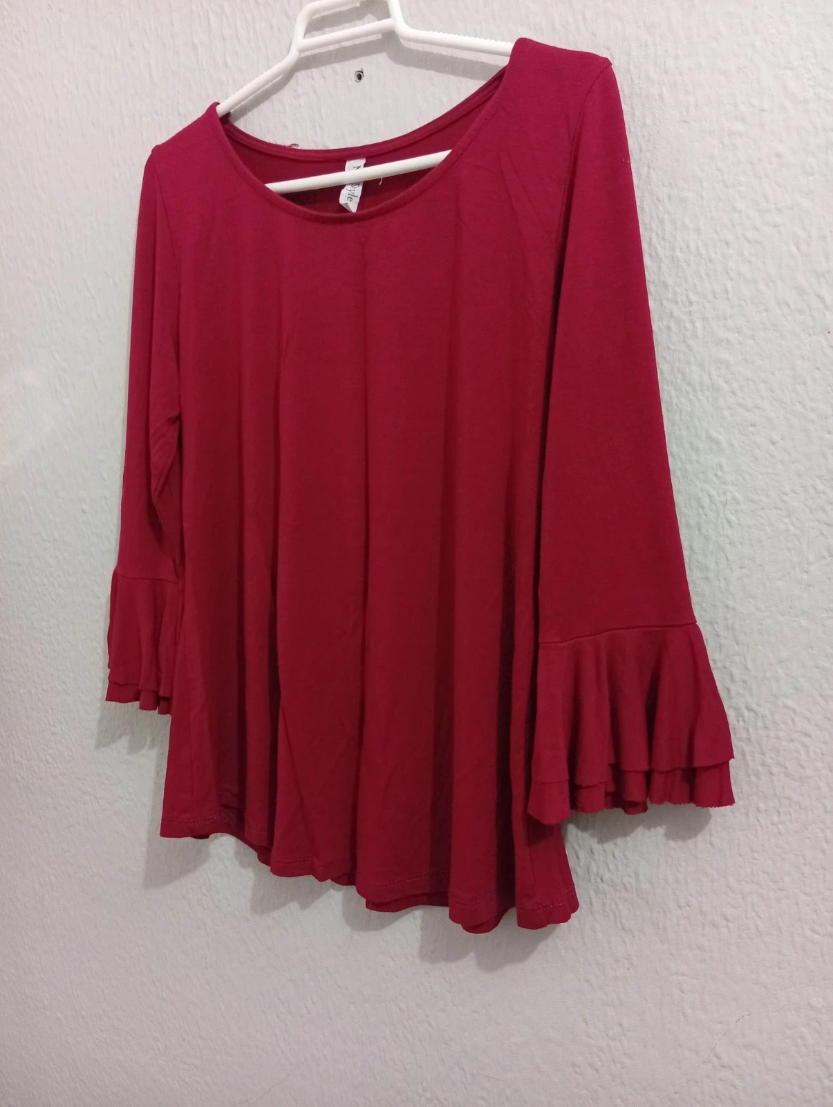 Burgundy blouse Features three-quarter bell sleeves and a round neckline.
