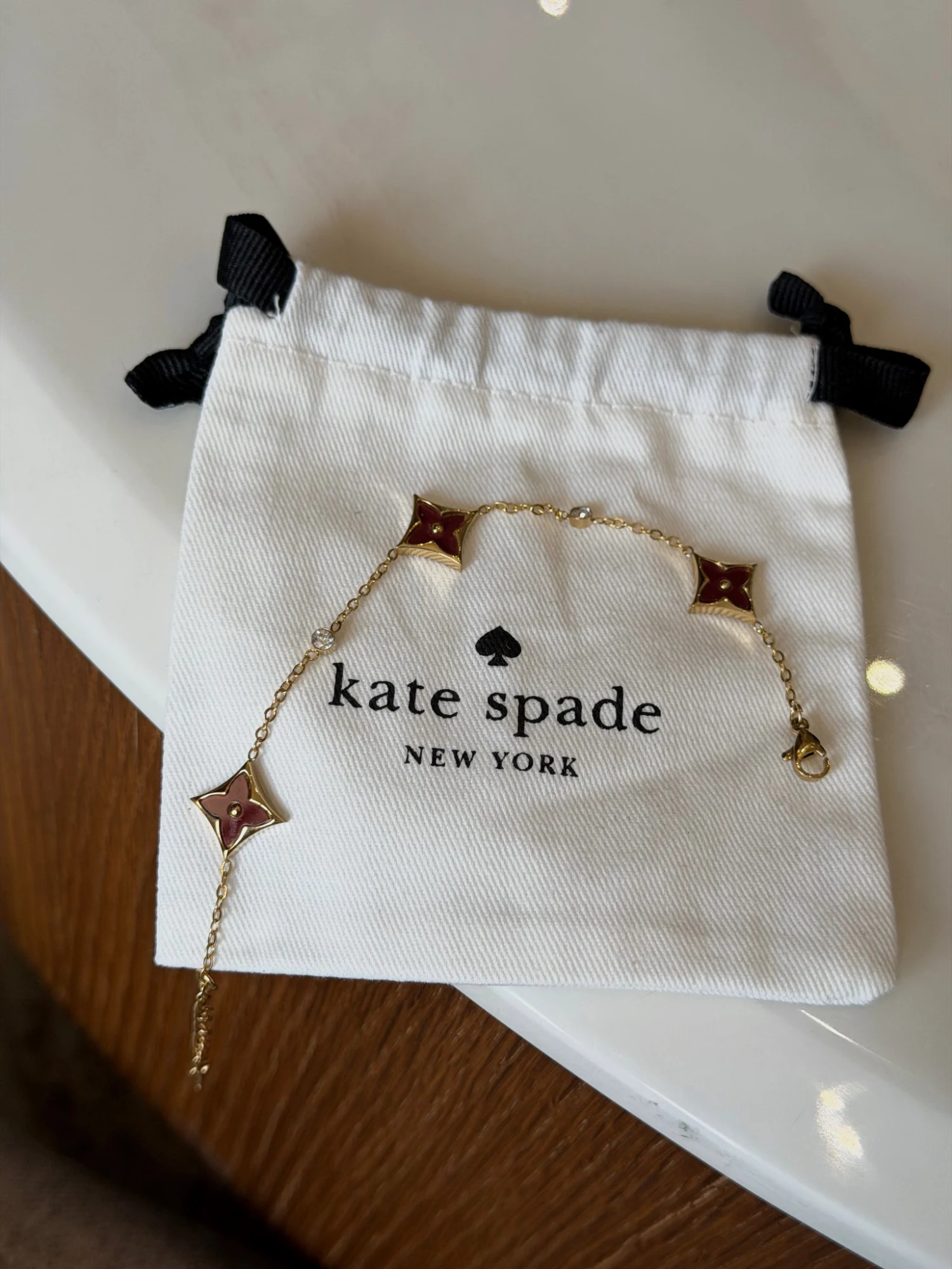 Bracelet Kate Spade doré à motifs trèfles bordeaux
