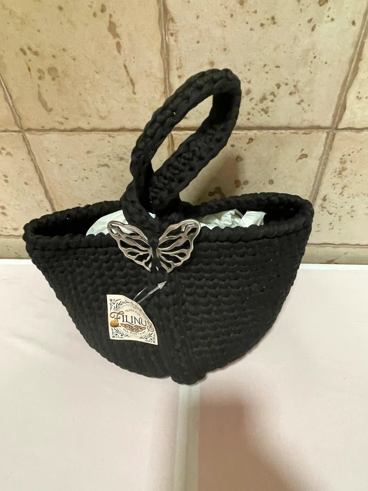 Bolso artesanal de trapillo negro con mariposa metálica.
