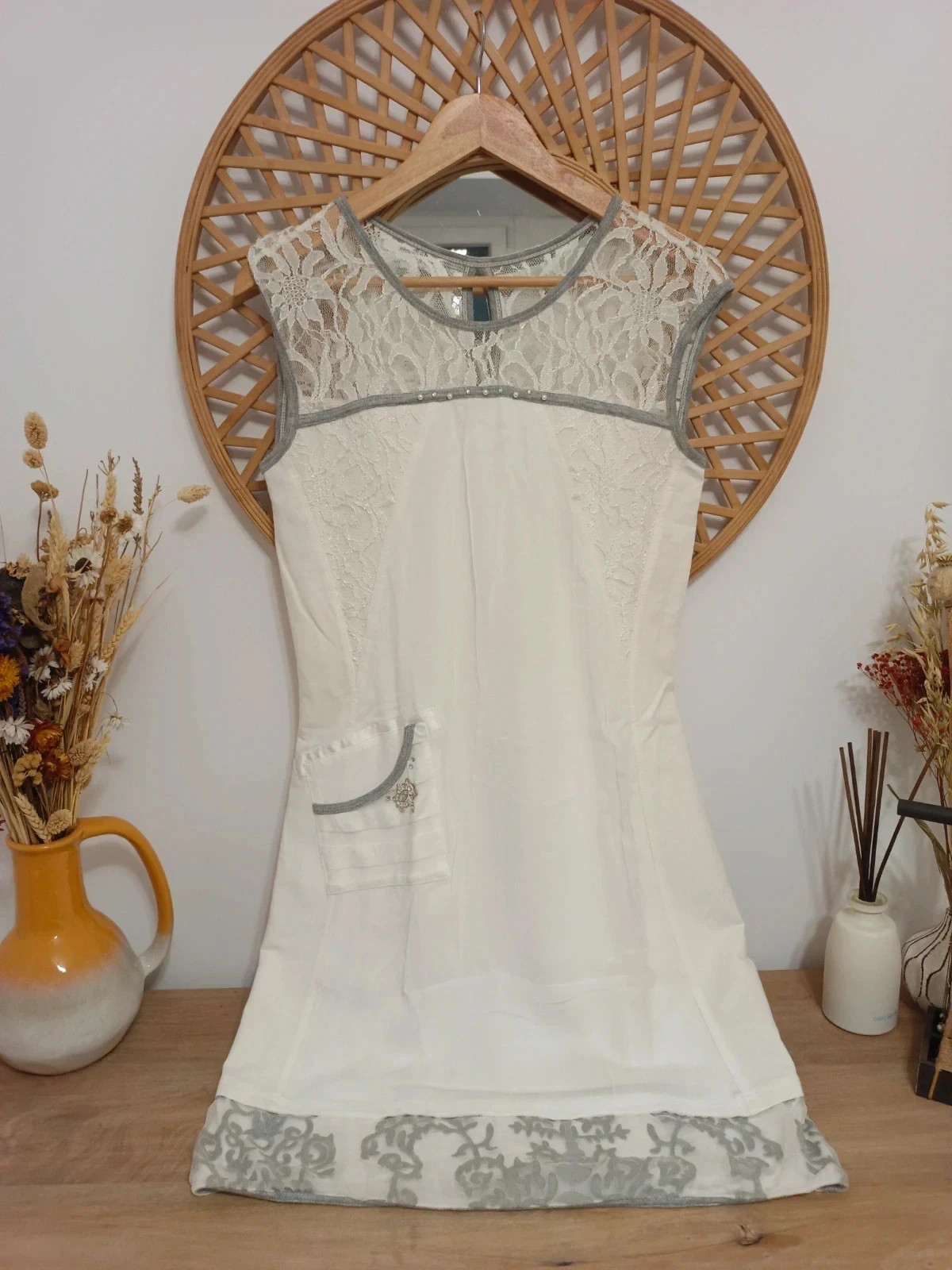Vestido blanco con detalles de encaje en los hombros y espalda, ribetes grises